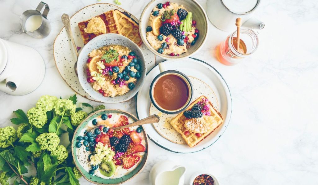 Bőséges reggeli esztétikusan elhelyezve egy asztalon, felülnézet. A cikkben a breakfast szót reprezentálja az angol etimológia tükrében.